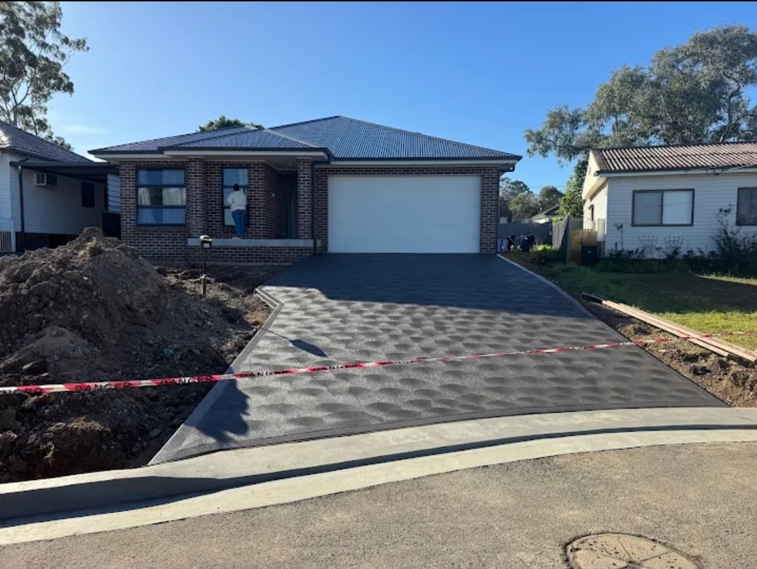 Finished decorative driveway in charcoal concrete running up to the garage of a new brick home