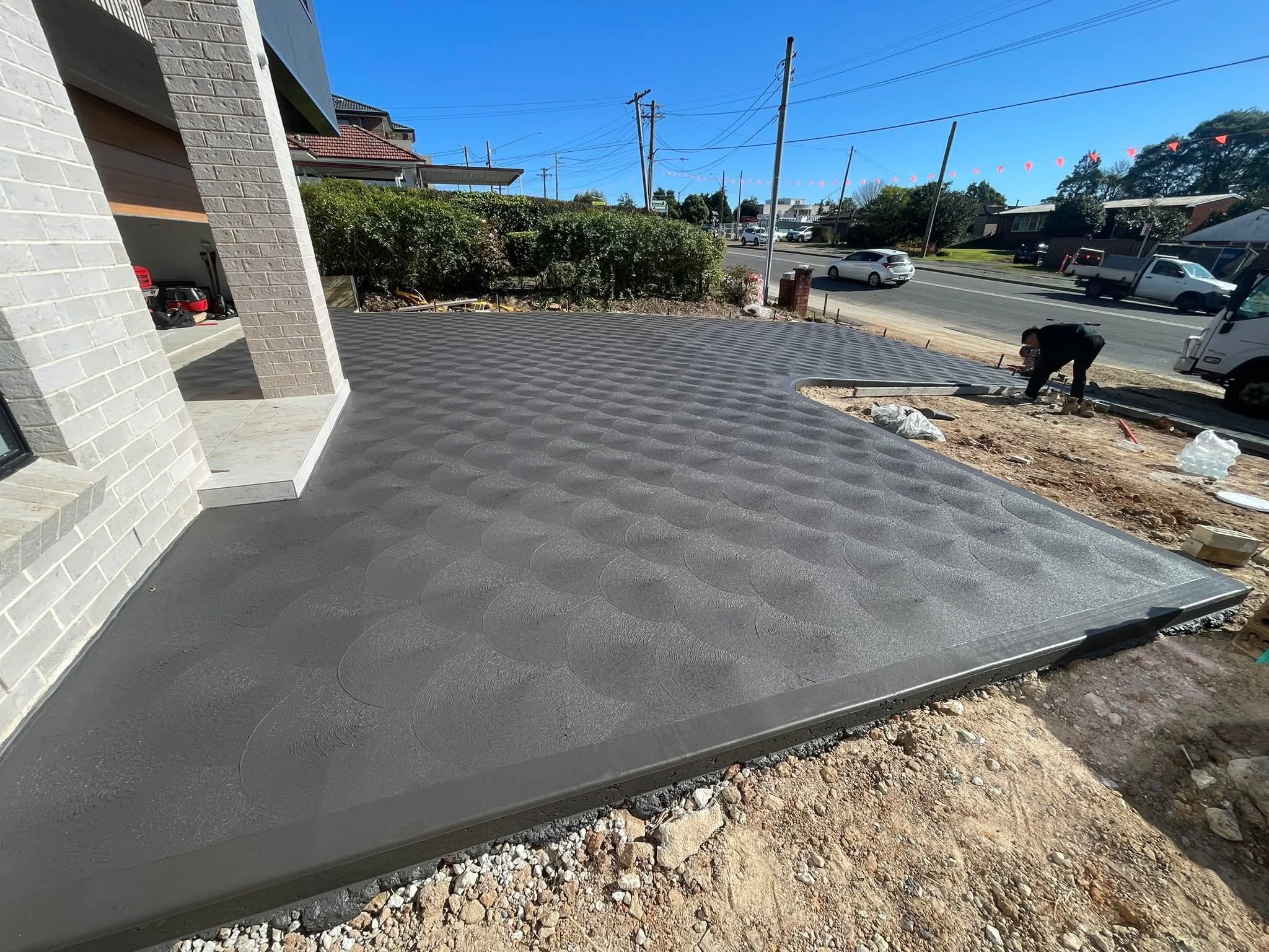 Large patterned concrete apron laid across the front of a light brick house