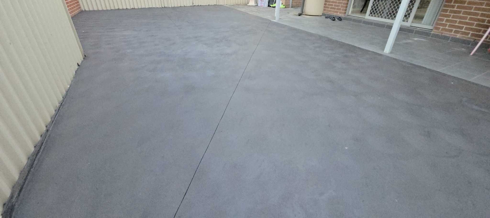 Finished rear courtyard slab with a clean control joint running through it